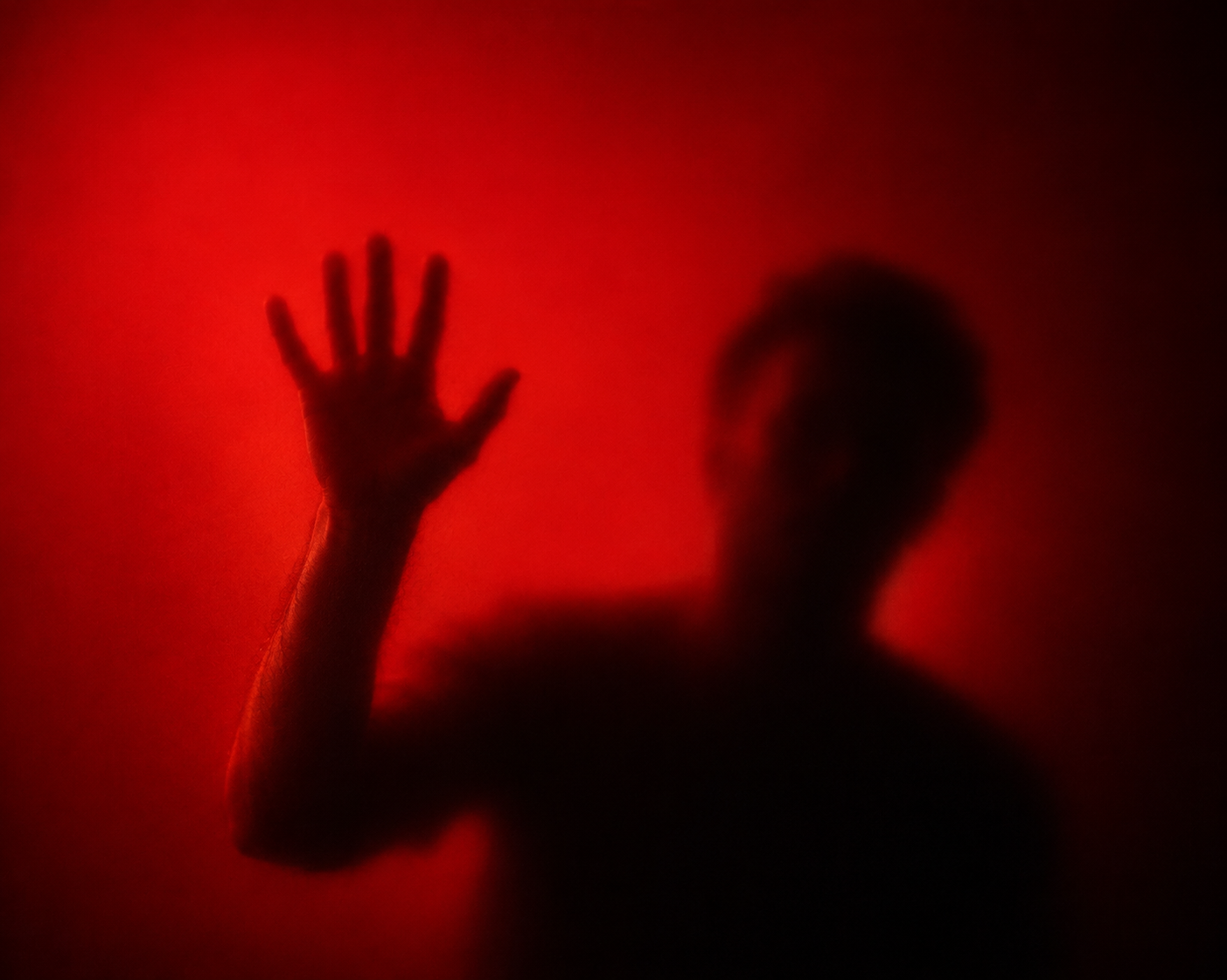 Generated study — a figure pressed against red backlit glass, one hand raised, the silhouette diffused